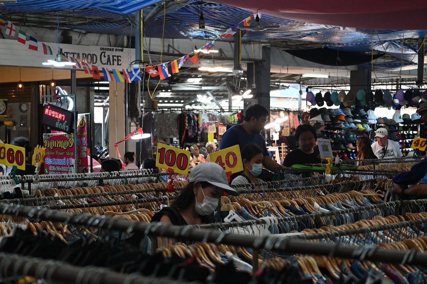 ลูกค้าเลือกเสื้อผ้าบนราวในตลาดในร่ม