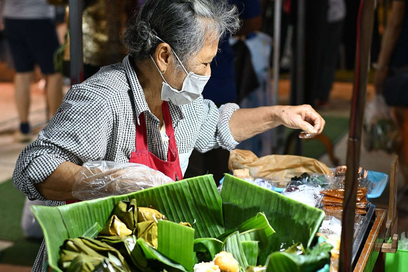 แม่ค้าจัดขนมห่อใบตองที่ตลาดกลางคืน